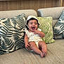 Zoe joined the competition — help win amazing prizes! baby, infant, smiling, sitting, couch, pillow, hat, romper, indoor, happy, child, cute, face, hand, foot, furniture, bookshelf, book, pattern, cozy