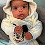 baby, infant, child, hooded_outfit, mickey_mouse, onesie, blue, white, big_eyes, hands, close_up, portrait, surprised_expression, plush, seat, blanket, indoor, cozy, eyelashes, pajamas