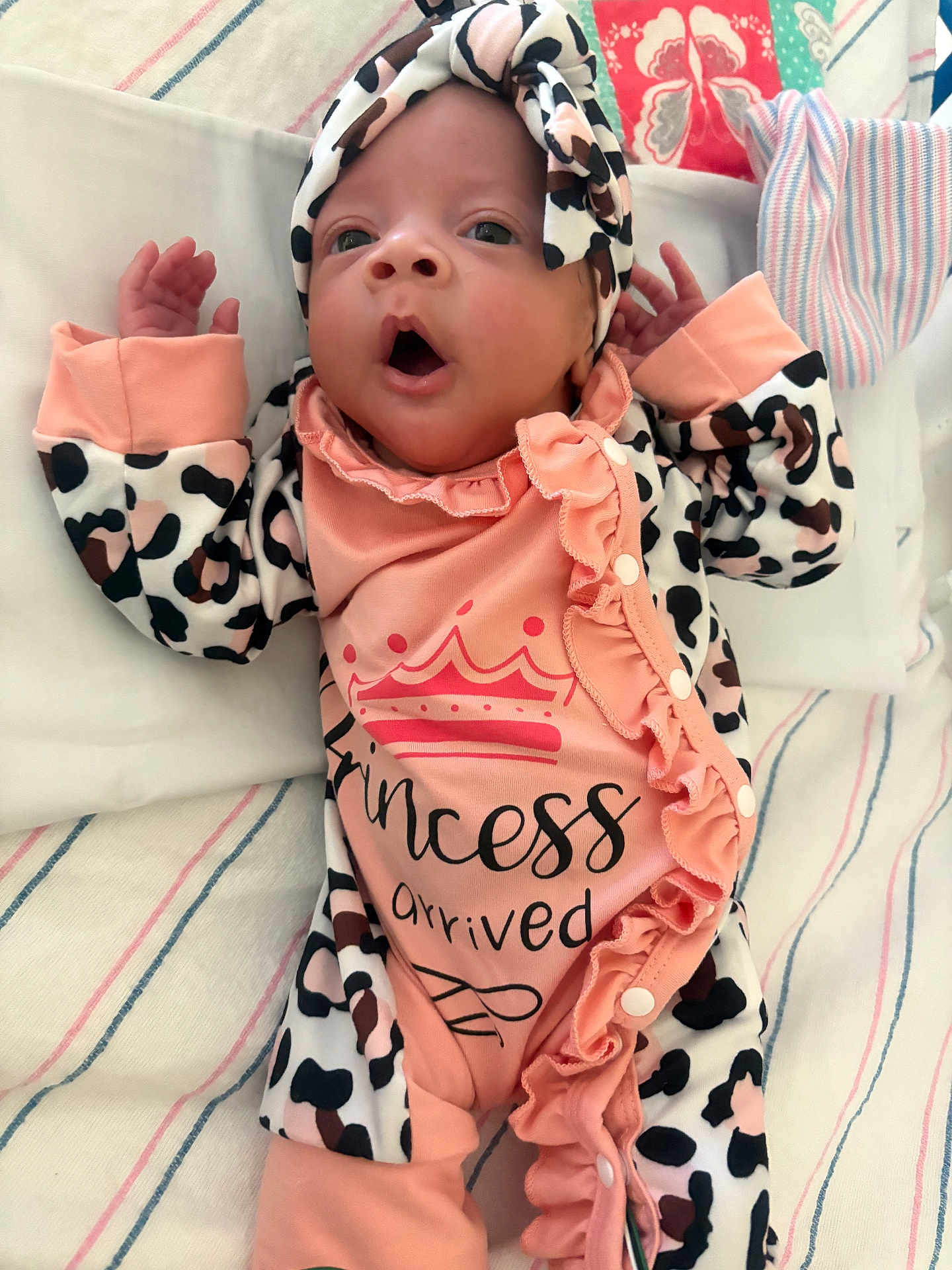 Amelia is registered to the contest to win money with this photo: baby, infant, newborn, clothing, headband, patterned_clothing, pink, leopard_print, blanket, striped, cute, face, expression, lying_down, child, small_hands, onesie, soft_texture, adorable, portrait