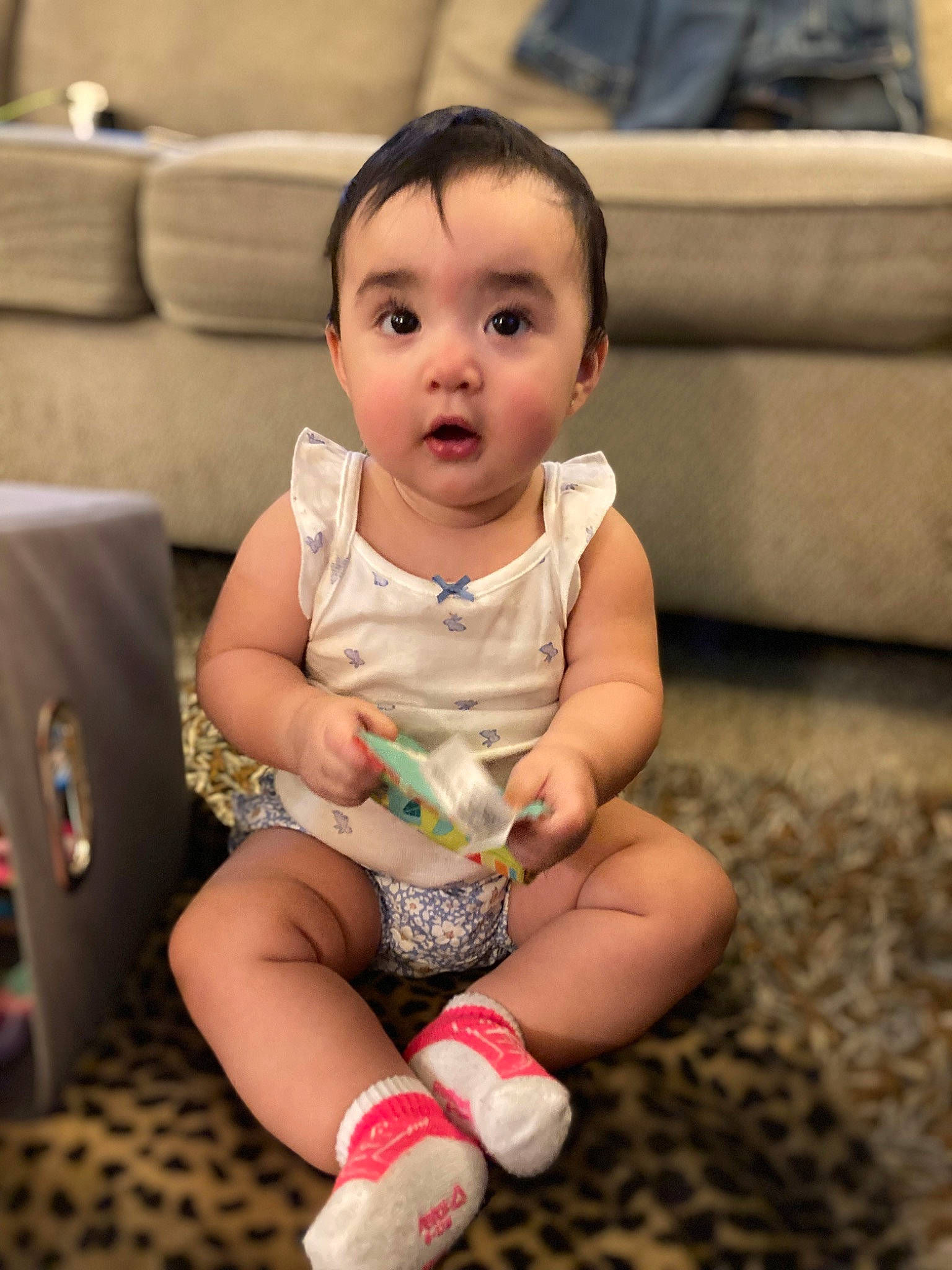 Avery is registered to the contest to win money with this photo: baby, baby_toddler_clothing, cheek, child, comfort, couch, eye, finger, flooring, fun, happy, head, human_leg, iris, person, skin, sleeve, smile, sock, surprise