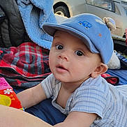 Milo is registered to the contest to win money with this photo: baby, child, blue_cap, blanket, colorful, curious, outdoor, car, face, wide_eyes, reaching, lying_down, plaid_blanket, soft_blanket, person, infant, close_up, casual, daytime, cute