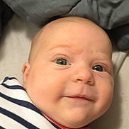 Jayce participe au concours pour gagner de l'argent avec cette photo : baby, infant, face, smile, striped_clothing, blue_eyes, blanket, soft_surface, cute, child, portrait, closeup, head, skin, expression, lying_down, indoors, cozy, young, person