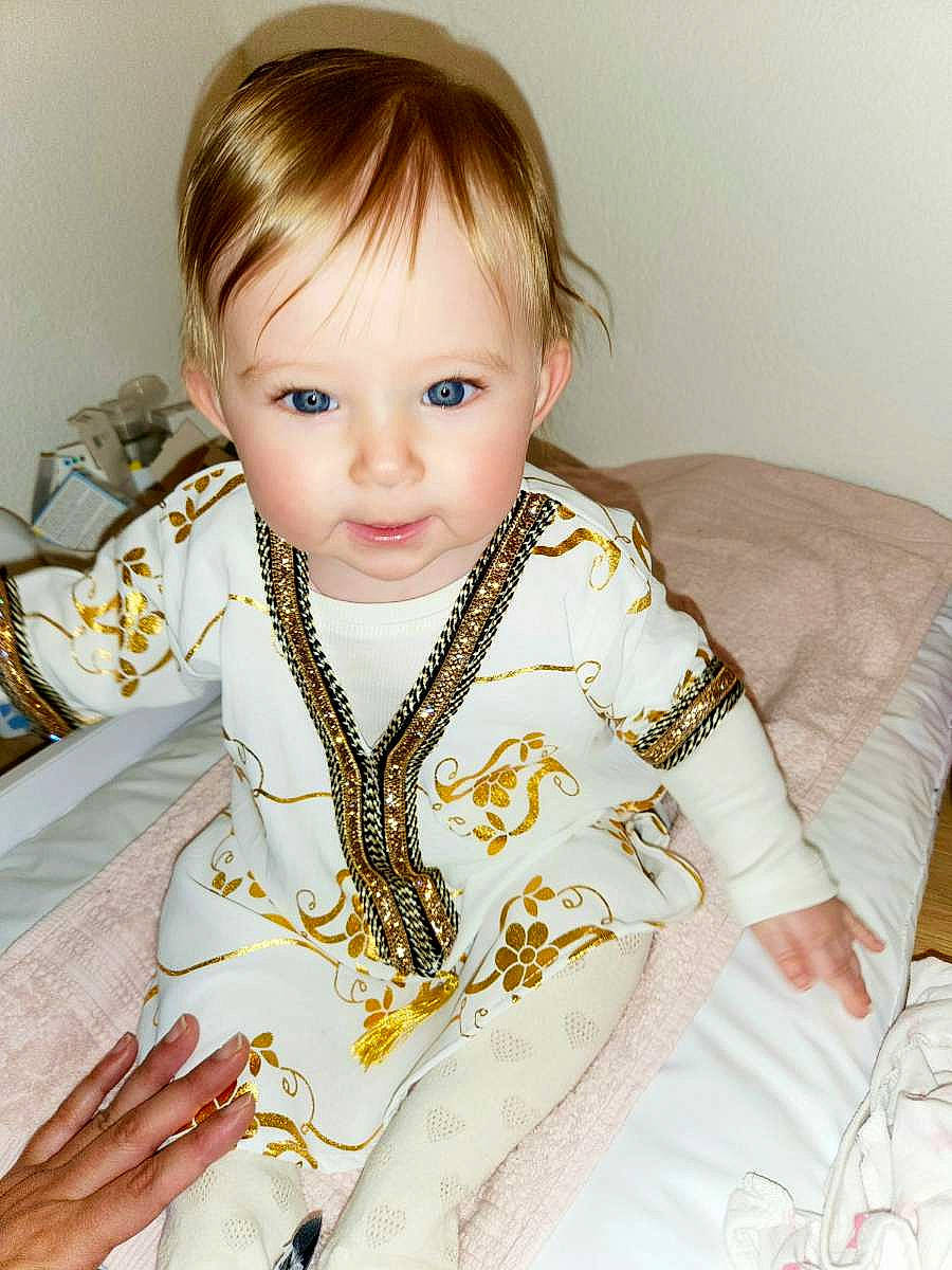 Inaya a rejoint le concours — aidez-le/la à gagner de superbes lots ! baby_toddler_clothing, blond, cheek, child, comfort, eyebrow, eyelash, facial_expression, fashion_design, head, iris, jewellery, linens, neck, pattern, person, sitting, skin, sleeve, t_shirt