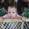 baby, blue_eyes, bubbles, baby_gate, indoor, child, curious, tongue_out, hand, wooden, plastic, person, seated, clothing, pink_shirt, messy_face, household_items, background, adult, floor