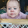 baby, child, face, blue_eyes, wet_hair, pink_clothing, baby_gate, wooden, bubbles, indoor, person, curious, closeup, portrait, home, furniture, blurred_background, candid, cute, expression