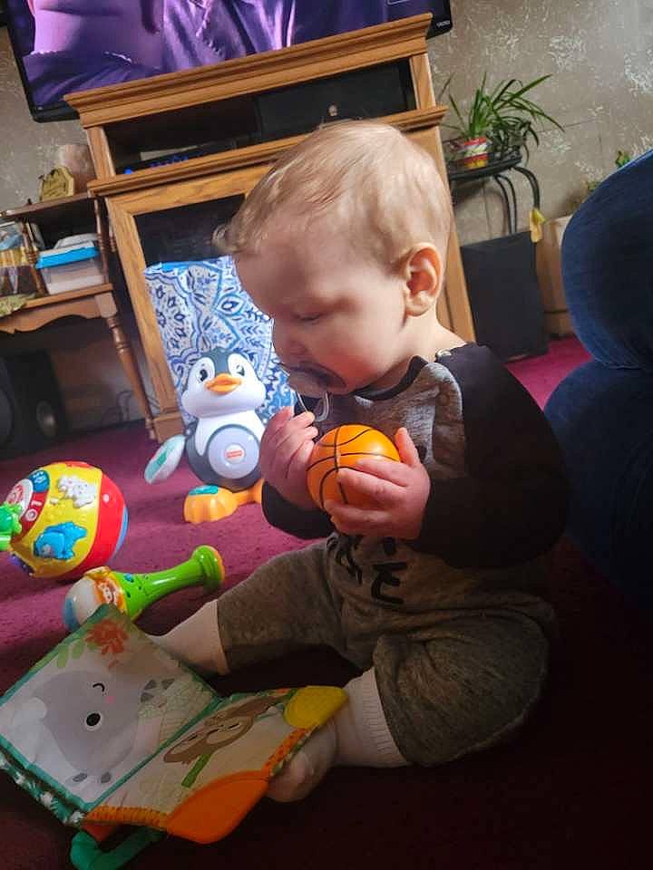 Storm is registered to the contest to win money with this photo: baby, baby_products, baby_toys, chair, child, flooring, flowerpot, fun, holiday, houseplant, lap, orange, person, plant, play, room, sitting, stuffed_toy, toddler, toy