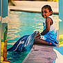 child, dolphin, water, pool, smile, outdoor, person, animal, marine_life, dock, blue_clothing, shorts, tank_top, cute, friendship, summer, sunlight, playing, nature, happy