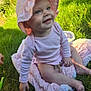 baby, child, pink_hat, pink_clothing, blanket, grass, outdoor, smiling, happy, sunlight, sitting, cute, infant, nature, headwear, toddler, skin, one_person, daylight, playful