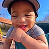 baby, blue_sky, cap, child, clothing, cute, daylight, expression, face, happy, infant, outdoor, person, playground, portrait, skin, smiling, sunlight, swing, young_child