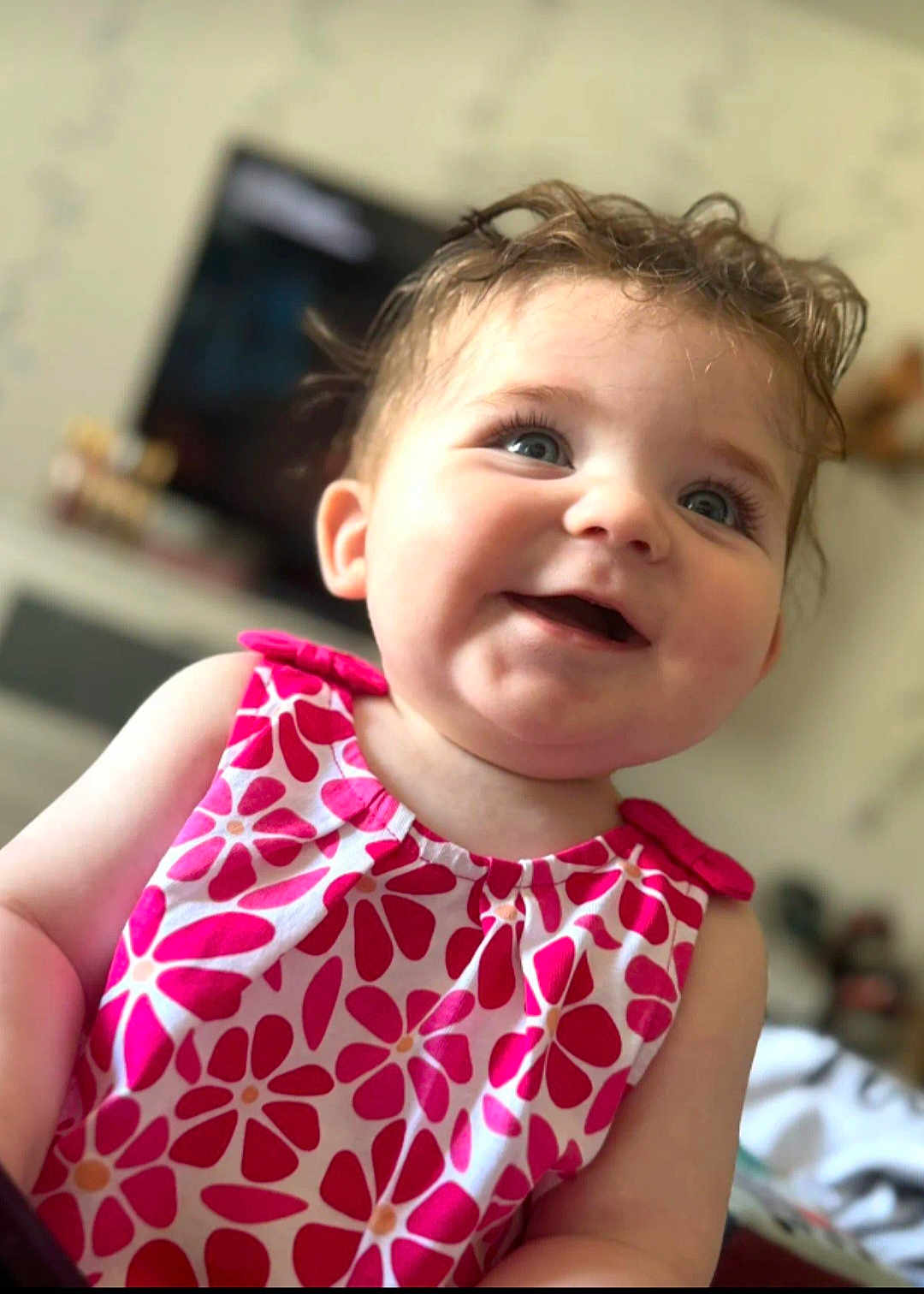 Ambre participe au concours pour gagner de l'argent avec cette photo : baby, child, smiling, blue_eyes, curly_hair, dress, floral_pattern, pink, white, indoor, portrait, happy, cute, infant, person, closeup, face, skin, young, domestic