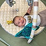 baby, infant, child, smiling, happy, portrait, play_mat, baby_gym, plush_toy, hanging_toy, pacifier, activity_bar, striped_toy, onesie, blanket, lying_down, indoor, playtime, face, photography