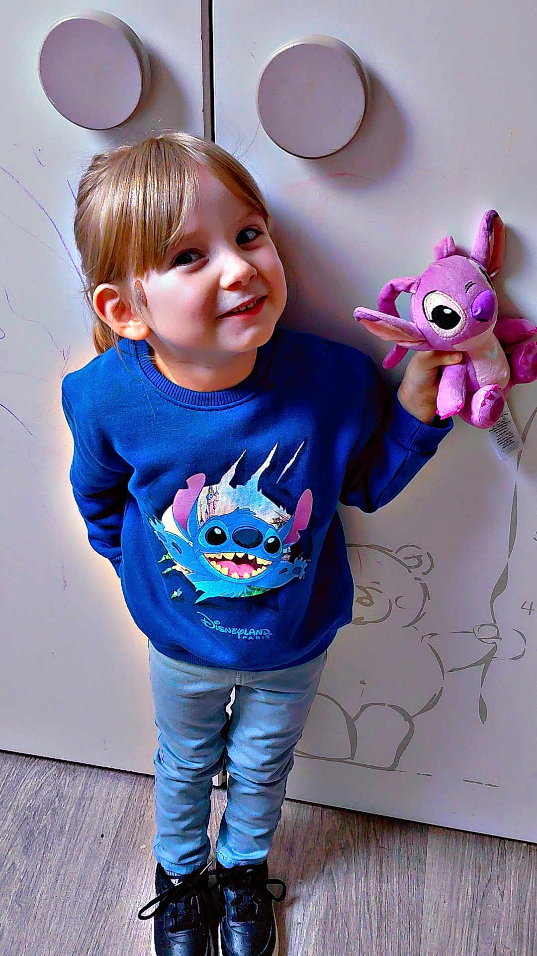 Keyla Claine participe au concours pour gagner de l'argent avec cette photo : balloon_drawing, black_shoes, blue_sweatshirt, casual_clothing, child, cute, door, drawing, happy, indoor, jeans, person, plush_toy, portrait, round_handles, smiling, stitch_character, teddy_bear_drawing, wooden_floor, young_child