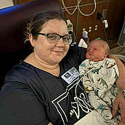 Wolfgang joined the competition — help win amazing prizes! adult, baby, bed, black_clothing, blanket, dinosaur_print, eyeglasses, hospital, infant, medical_equipment, newborn, person, portrait, resting, smile, sleeping, toddler, woman, wristband, young_child