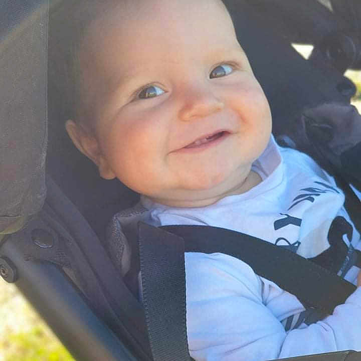 Jaden participe au concours pour gagner de l'argent avec cette photo : baby, black_strap, child, closeup, comfort, cute, daylight, face, happy, harness, infant, outdoor, person, portrait, seat, smiling, stroller, sunlight, white_shirt, young_child