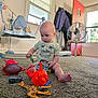 toddler, child, toy, carpet, indoor, phone_toy, plastic_toy, giraffe_toy, fan, coat, window, door, baby_swing, car_toy, foot, shirt, person, floor, room, curious