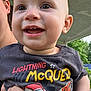 Joseph is registered to the contest to win money with this photo: baby, child, smiling, face, person, clothing, shirt, outdoor, porch, hand, eyes, happy, head, lightning_mcqueen, cartoon, red, black_shirt, teeth, skin, nature