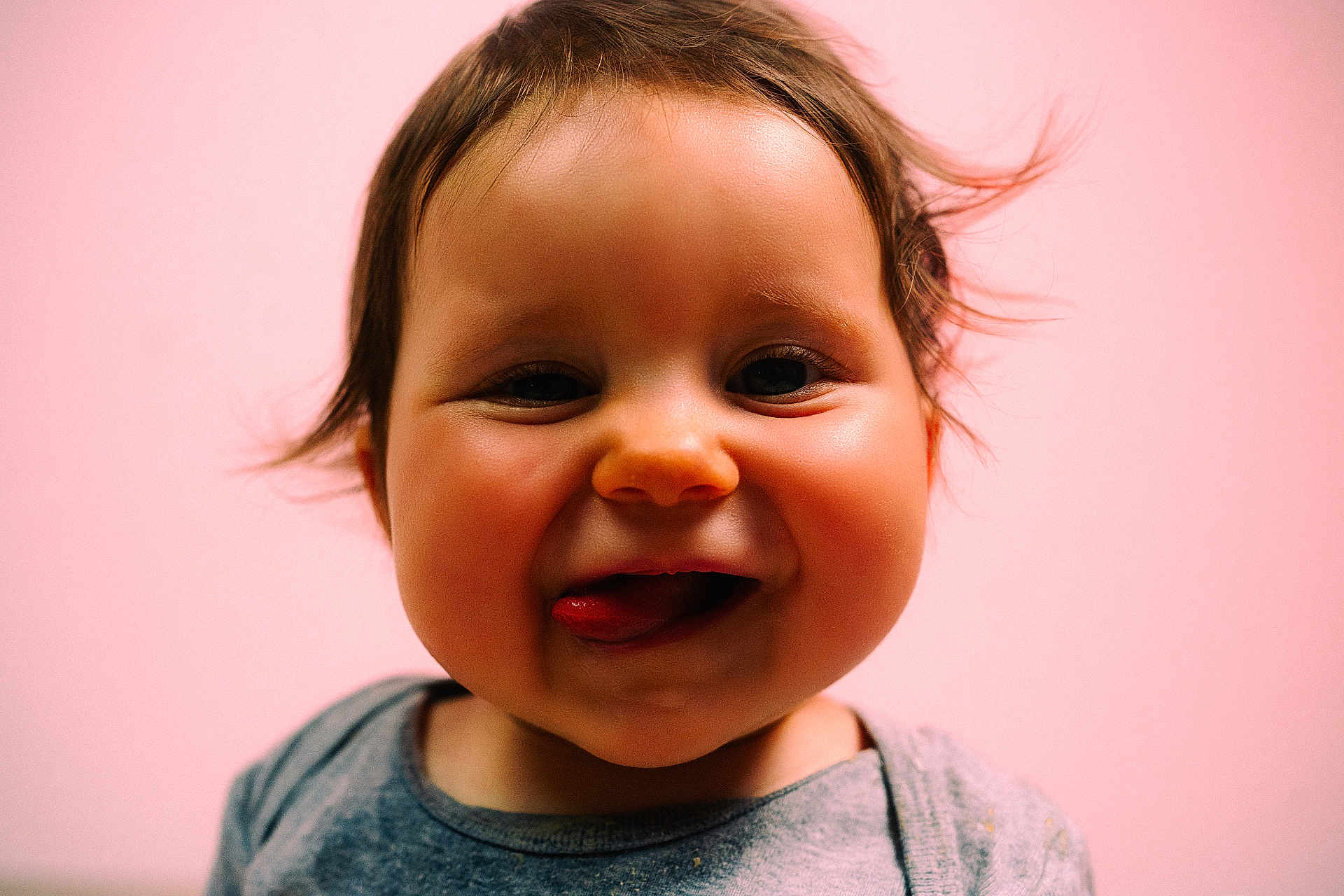 éléonore participe au concours pour gagner de l'argent avec cette photo : baby, face, tongue, smile, cheeks, child, portrait, cute, happy, pink_background, young, infant, expression, clothing, hair, skin, closeup, one_person, indoors, playful