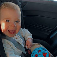 Xavier is registered to the contest to win money with this photo: accessories, baby, belt, bodypart, car, clothing, coat, cushion, face, happy, head, homedecor, jacket, mouth, person, photography, portrait, smile, transportation, vehicle