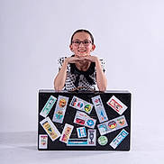Olivia joined the competition — help win amazing prizes! accessories, child, cute, dress, fashion, girl, glasses, happy, indoor, person, playful, polka_dot, portrait, posing, smiling, studio, suitcase, travel_stickers, white_background, young