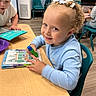 child, children, classroom, school, student, smiling, portrait, sitting, desk, table, marker, activity_book, notebook, colorful, chairs, indoor, learning, art, curly_hair, classmates