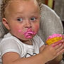 toddler, child, curly_hair, cupcake, pink_frosting, high_chair, face_paint, messy, food, snack_time, indoor, baby, cheeks, hands, table, clothing, person, expression, sitting, portrait
