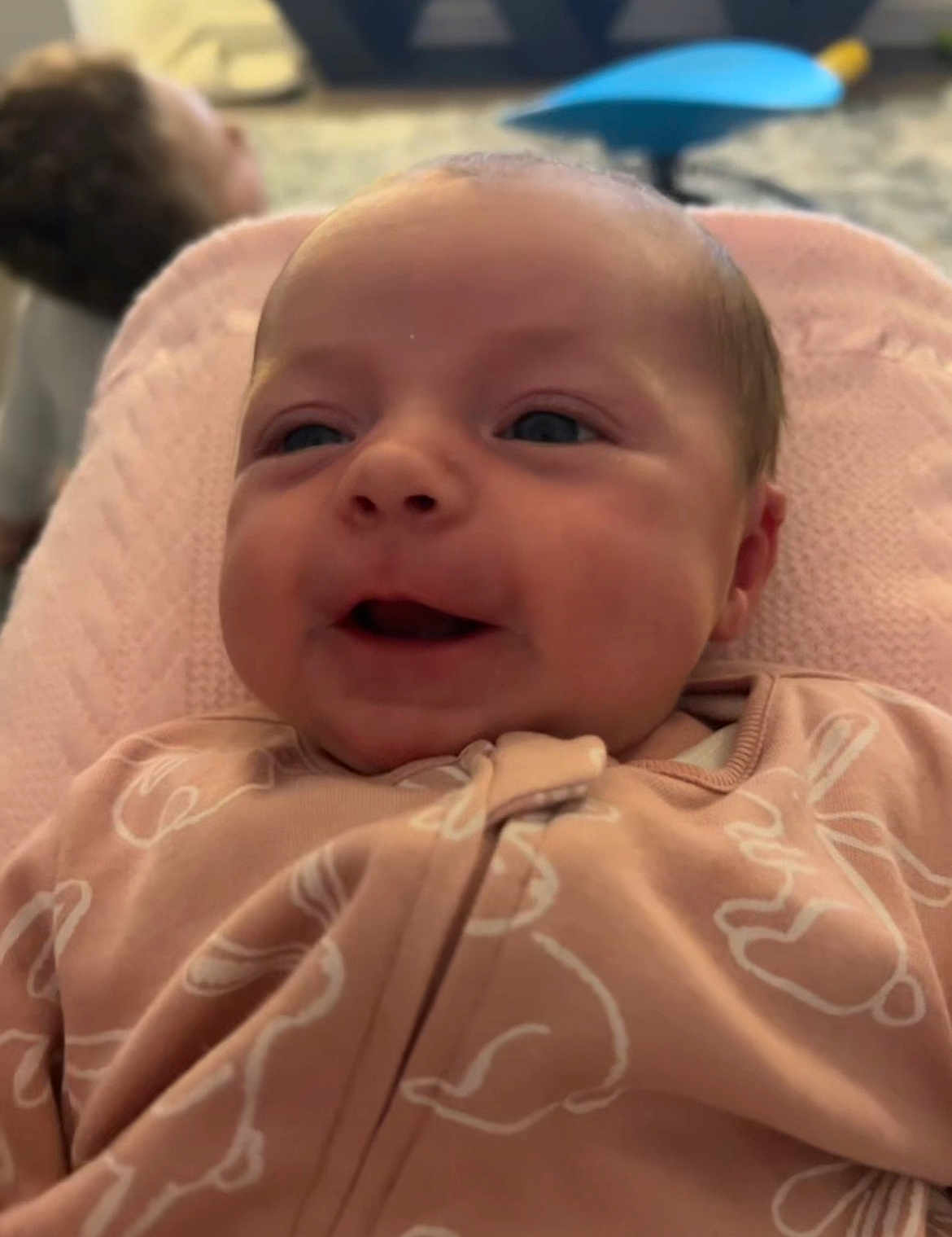 Esmè is registered to the contest to win money with this photo: baby, child, smile, pajamas, pink, blanket, face, portrait, infant, clothing, cute, happy, indoor, person, young_child, blurred_background, soft_texture, cozy, resting, newborn