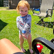 Ariela joined the competition — help win amazing prizes! toddler, child, red_hair, barefoot, smiling, long_sleeve_shirt, diaper, bubbles, grass, outdoor, sunny, garden_chair, toy, playful, greenery, daylight, happy, person, lawn, summer