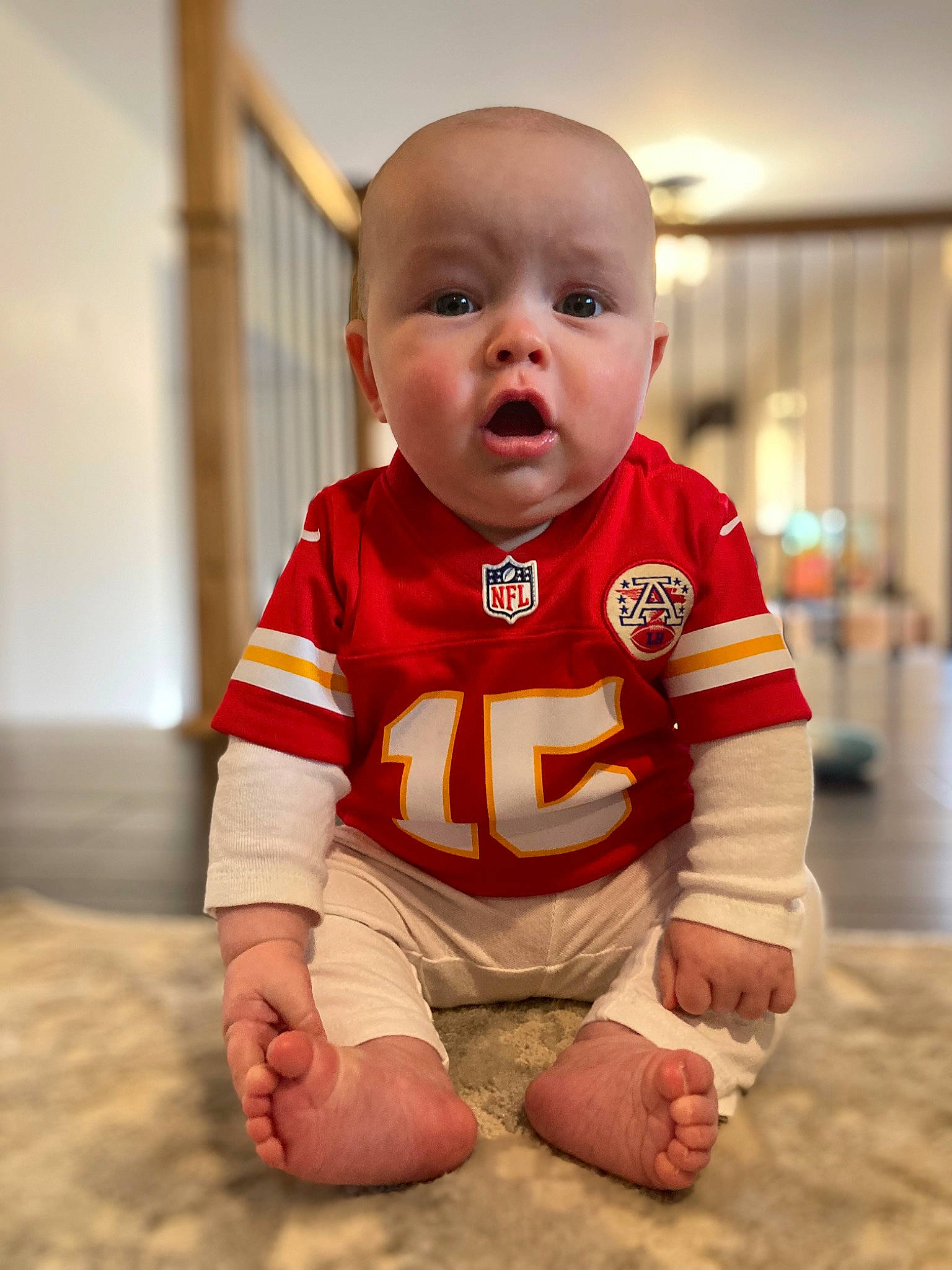 Owen is registered to the contest to win money with this photo: baby, baby_toddler_clothing, barefoot, carmine, child, floor, flooring, foot, fun, happy, human_leg, knee, orange, person, skin, sleeve, sportswear, surprise, t_shirt, thigh