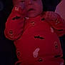 baby, infant, child, halloween, orange_clothing, onesie, pacifier, lying_down, cute, face, hand, dark_background, indoor, soft_toy, expression, portrait, newborn, sleepwear, bat_pattern, ghost_pattern