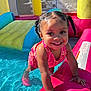 toddler, child, smile, swimsuit, water, inflatable_pool, braided_hair, outdoor, sunlight, summer, play, fun, happy, pool, colorful, toy, splash, young_child, cute, person