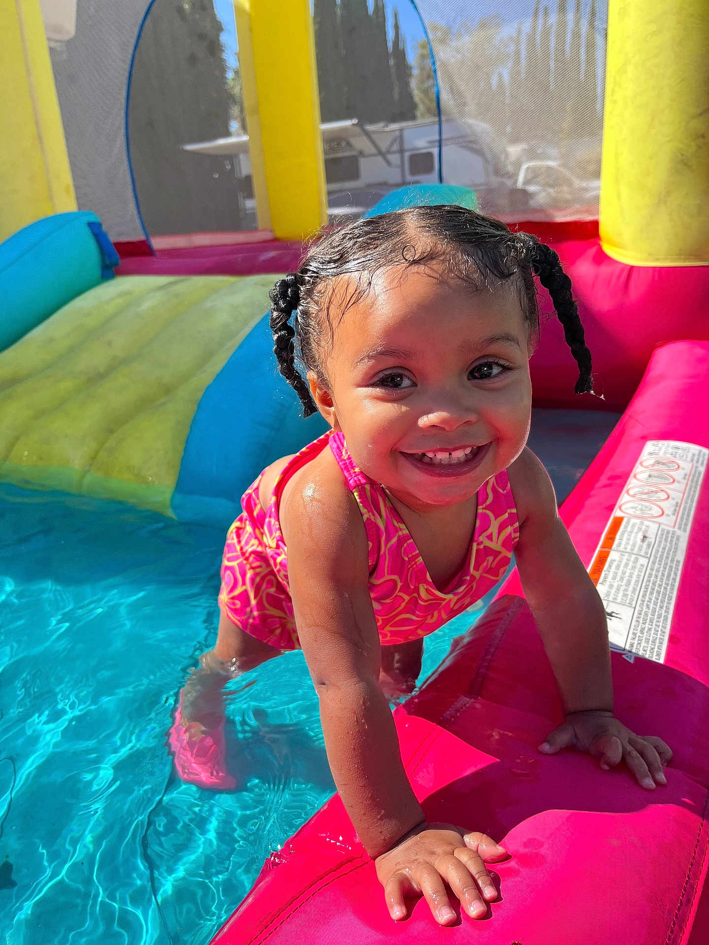 Lylah is registered to the contest to win money with this photo: toddler, child, smile, swimsuit, water, inflatable_pool, braided_hair, outdoor, sunlight, summer, play, fun, happy, pool, colorful, toy, splash, young_child, cute, person