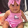 apparel, baby, blanket, bow, child, chubby_cheeks, cute, dress, face, foot, hand, happy, headband, hello_kitty, indoors, infant, person, pink, sitting, smile