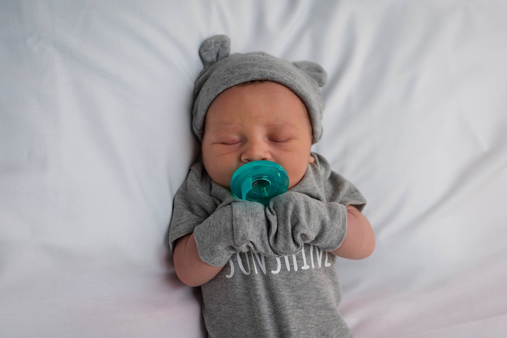 Carter is registered to the contest to win money with this photo: arm, baby, baby_toddler_clothing, cap, clothing, comfort, eye, face, flash_photography, gesture, grey, hand, happy, head, headwear, iris, mouth, nose, outerwear, person
