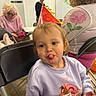 Hollie is registered to the contest to win money with this photo: child, toddler, birthday, party_hat, tongue_out, portrait, smiling, sitting, sweatshirt, cartoon, chairs, indoor, family, elderly_person, glasses, background, celebration, colorful, playful, candid
