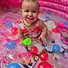Abriella is registered to the contest to win money with this photo: baby, beaded_necklace, child, colorful, cute, fun, happy, inflatable_pool, outdoor, person, pink, playful, pool, sitting, smiling, summer, swimsuit, tongue_out, water, water_balloons
