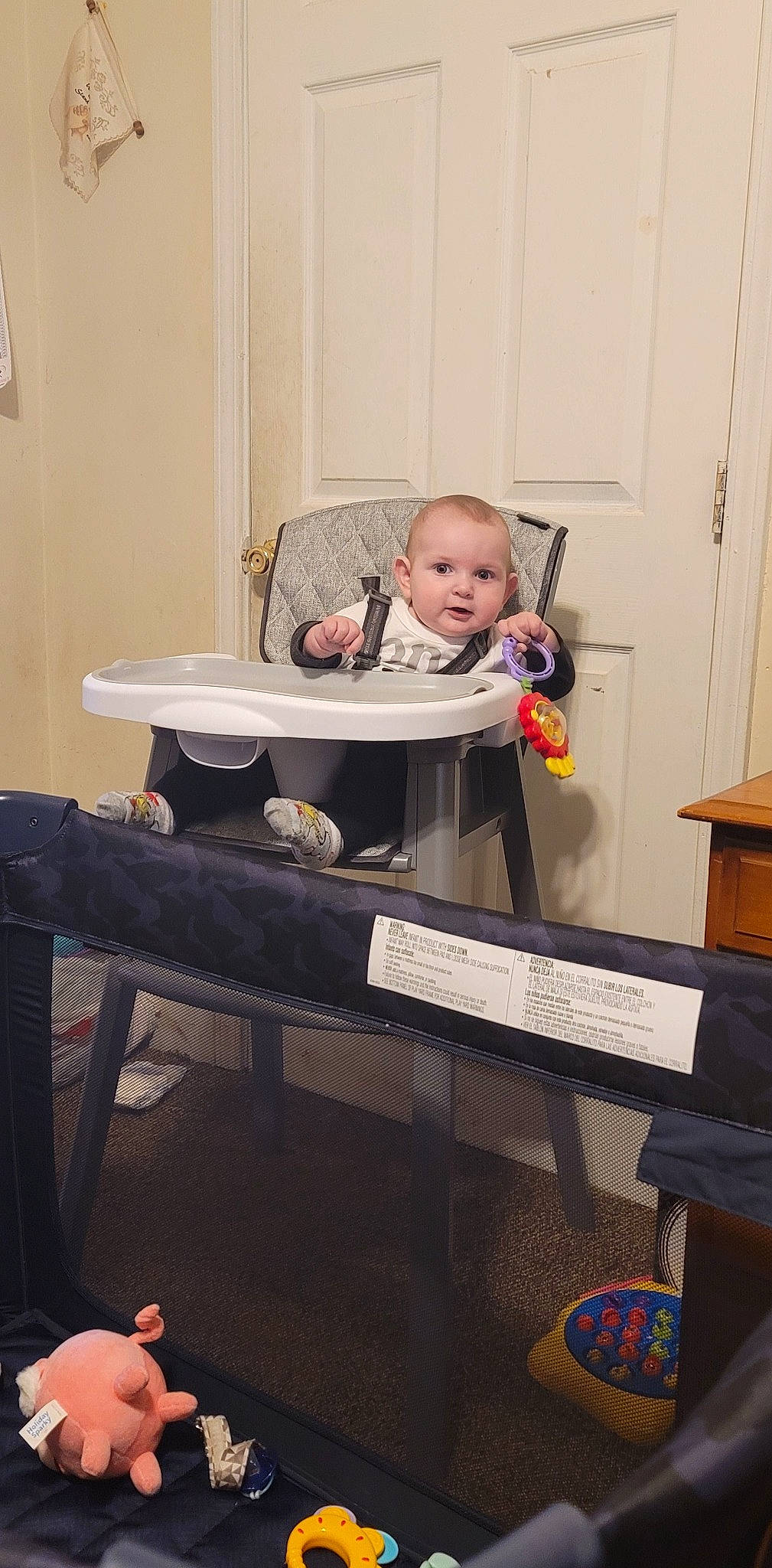 Ashton is registered to the contest to win money with this photo: baby, baby_products, baby_toddler_clothing, chair, child, comfort, desk, door, flooring, hardwood, logo, person, play, room, sitting, t_shirt, table, toddler, wood