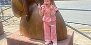 Lilly-Sue is registered to the contest to win money with this photo: bee, building, casual, child, city, concrete, daylight, fun, happy, outdoor, peace_sign, person, pink_clothing, playful, railing, sidewalk, statue, tongue_out, urban, wooden_sculpture