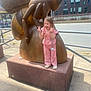 Lilly-Sue is registered to the contest to win money with this photo: child, pink_clothing, statue, wooden_sculpture, bee, peace_sign, tongue_out, sidewalk, urban, playful, outdoor, daylight, concrete, building, railing, happy, person, casual, fun, city