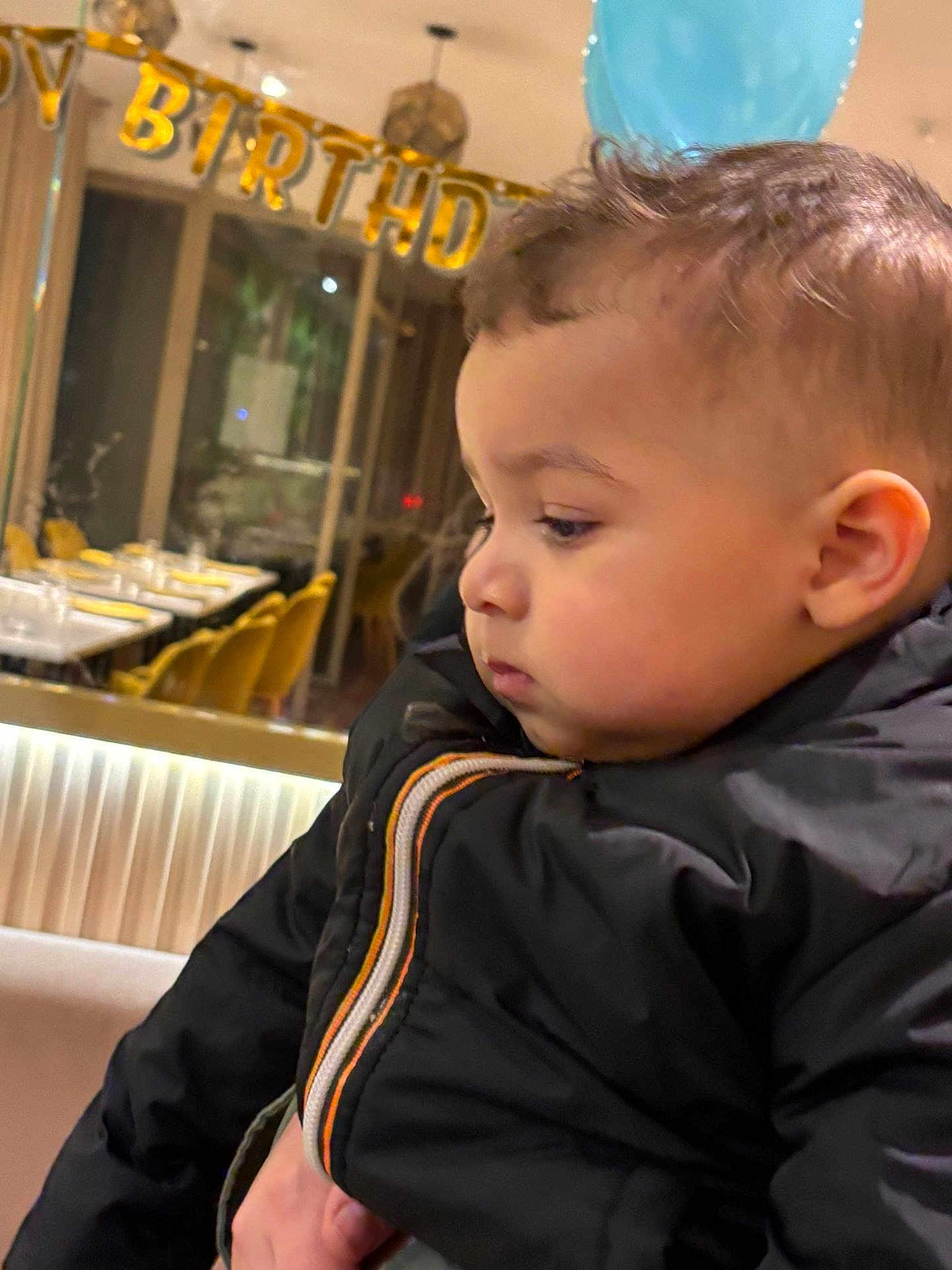 Jad a rejoint le concours — aidez-le/la à gagner de superbes lots ! child, toddler, baby, profile, birthday_banner, party, jacket, coat, indoor, restaurant, dining_table, chairs, celebration, portrait, pensive, cheeks, hair, close_up, person, festive