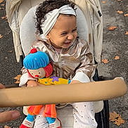 Anna participe au concours pour gagner de l'argent avec cette photo : autumn, boots, casual, child, clothing, clown_doll, curly_hair, cute, happy, headband, jacket, laughing, leaves, outdoor, pavement, person, playful, stroller, toddler, toy