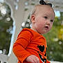 Allison joined the competition — help win amazing prizes! baby, casual_clothing, child, closeup, curious, cute, daylight, expression, face, fall, greenery, headband, orange_shirt, outdoor, person, porch, portrait, pumpkin_face, toddler, young_child
