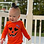 bow, casual_clothing, child, cute, daylight, expression, fall, happy, headwear, nature, orange_clothing, outdoor, person, playful, porch, railing, smile, toddler, walking, young_child