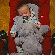 Ezio participe au concours pour gagner de l'argent avec cette photo : baby, sleeping, pacifier, teddy_bear, plush_toy, red_baby_seat, wooden_floor, pajamas, infant, cute, cozy, indoor, child, peaceful, relaxation, soft_toy, heart_emoji, flooring, comfort, rest