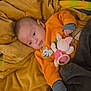 Ezio participe au concours pour gagner de l'argent avec cette photo : baby, infant, blanket, plush_toy, orange_clothing, face, blue_eyes, couch, soft_toy, cozy, child, lying_down, comfort, fabric, cute, indoor, colorful, warm, resting, young_child