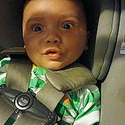 Karson joined the competition — help win amazing prizes! baby, infant, child, car_seat, harness, seatbelt, vehicle, sitting, portrait, face, wide_eyes, open_mouth, looking_at_camera, green_clothing, indoor, close_up, photograph, safety, padded_seat, travel