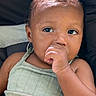 baby, child, infant, portrait, close_up, face, eyes, hand, fist, chewing, curious, serious, sitting, car_seat, vehicle, earring, tank_top, clothing, indoor, photography