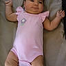 baby, infant, onesie, pink_clothing, lying_down, soft_bedding, indoor, child, cute, chubby, smiling, relaxed, baby_girl, infant_toddler, face, skin, arms, legs, head, sleeping_area
