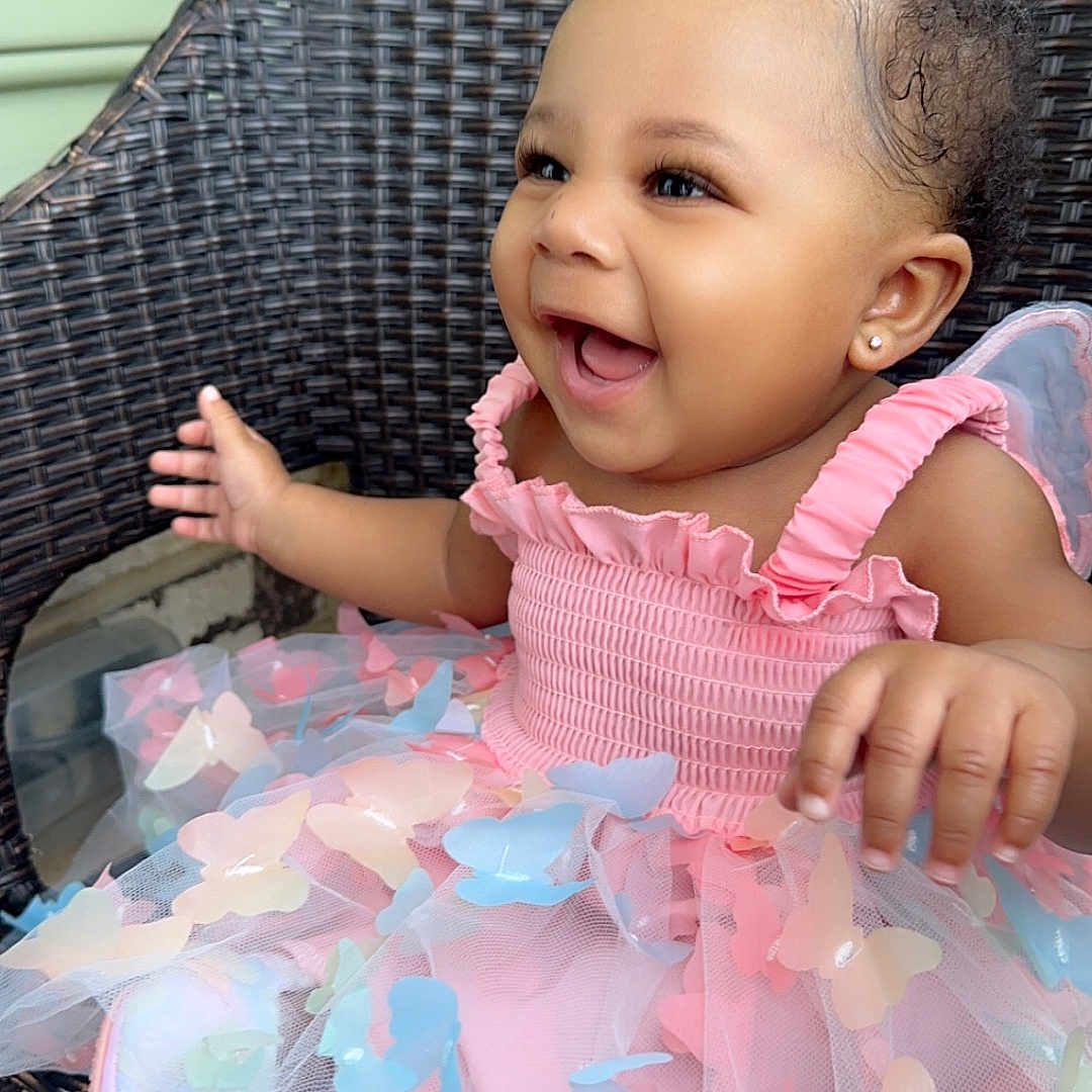 Damiyah is registered to the contest to win money with this photo: baby, butterfly, chair, child, curly_hair, cute, dress, earring, fashion, happy, indoor, infant, pink_dress, playful, portrait, sitting, smiling, toddler, tulle, woven_chair