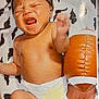 Jase is registered to the contest to win money with this photo: baby, newborn, crying, diaper, infant, toy, football, blanket, dinosaur_pattern, skin, hand, foot, lying_down, indoor, child, expression, emotion, closeup, person, cute