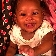 Keziah is registered to the contest to win money with this photo: baby, smiling, happy, infant, face, hand, blanket, clothing, pattern, earrings, curly_hair, seat, pink, blue, cute, portrait, child, toddler, indoor, skin